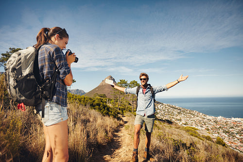 Woman photographing her boyfriend while hiking