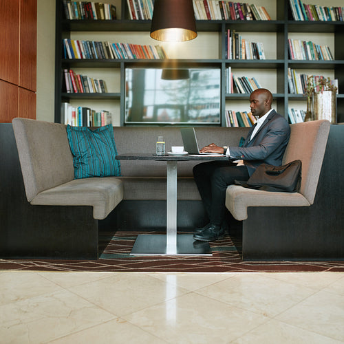 African businessman working on laptop at cafe