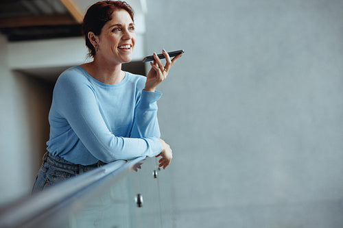 Happy business woman speaking in a phone call conversation on an interior balcony