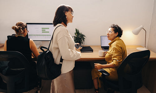 Three colleagues discussing work in a modern office setting