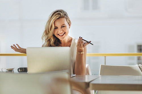 Businesswoman looking at laptop and smiling at cafe