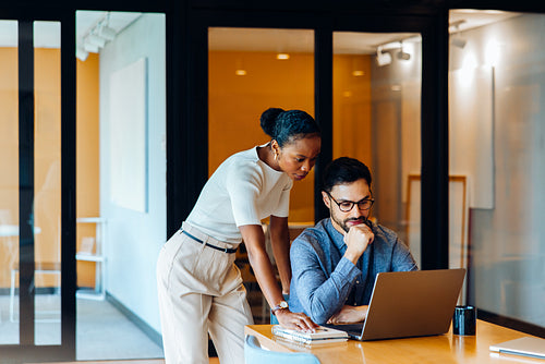 Two professionals analyzing data on a laptop in an office environment