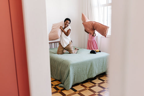Playful mother and daughter having fun with pillows in a bedroom