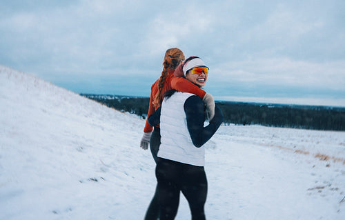 Two friends enjoy a playful winter walk in snowy landscape