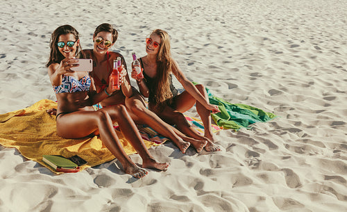 Women sitting at the beach taking a selfie