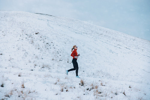 Snowy running carries the woman across open winter terrain during outdoor fitness