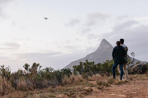 Young couple navigating a flying drone in sky