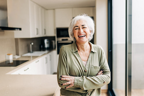 Carefree elderly woman laughing happily in her home