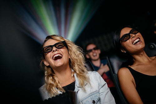 Smiling female friends watching 3d movie