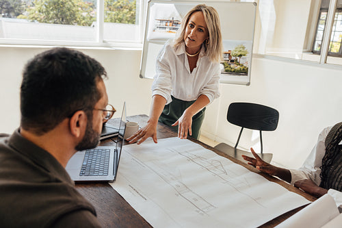 Professional architects discussing building plans at a modern architectural firm