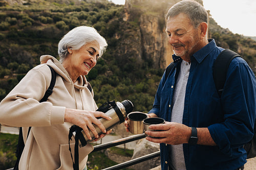 Mature couple taking a coffee break while hiking in the mountain
