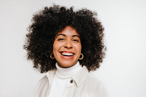 Young woman with curly hair smiling at the camera in a studio