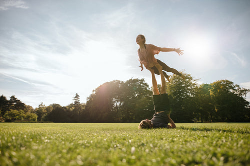 Healthy young couple doing acrobatic yoga at park