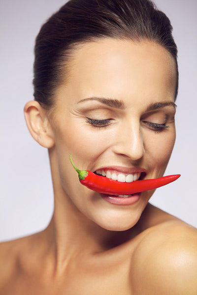 Young beauty biting red chili pepper