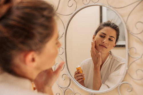 Female applying cream onto her face