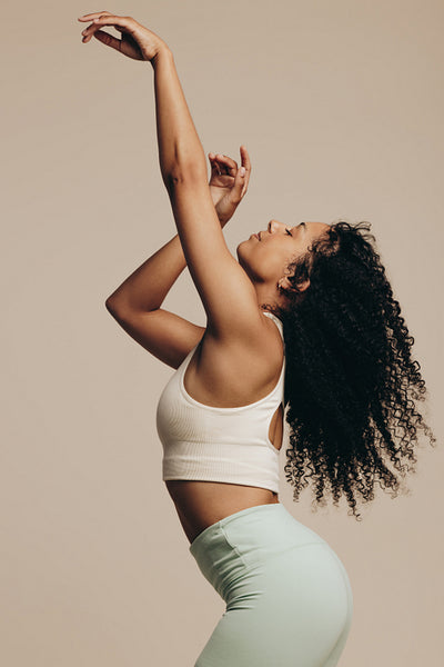 Fit young woman doing an expressive dance move in fitness clothing