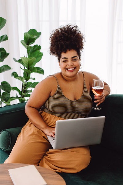 Woman sitting at home with wine and laptop