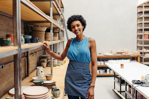 Cheerful young ceramist smiling at the camera in her pottery