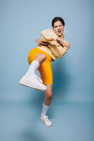 Energetic young woman winking at the camera while dancing in a studio
