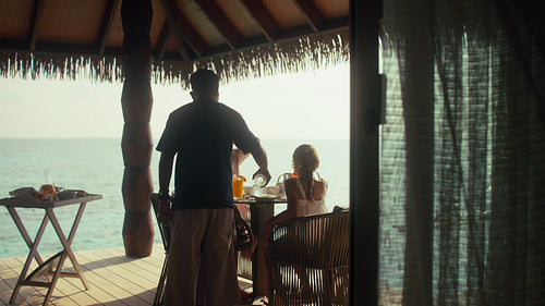 Family enjoys an idyllic private breakfast on their overwater villa patio at a tropical resort