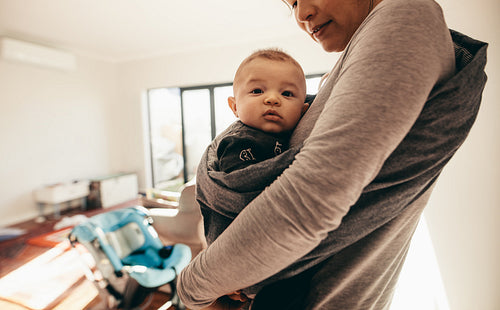Mother carrying her baby in a baby wrap carrier