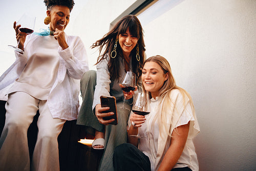 Friends enjoying an evening with wine and laughter on a balcony
