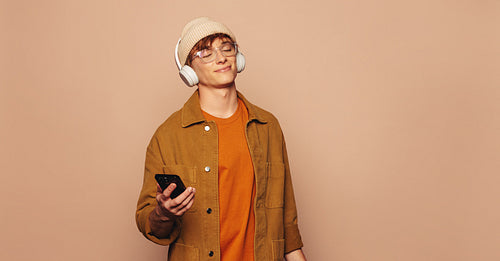 Casual man listening to music on peach studio background