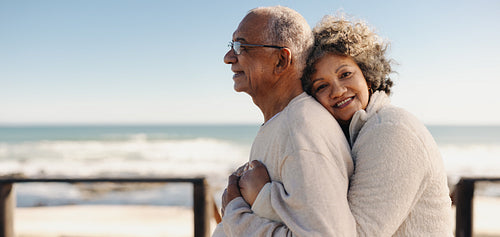 Romantic senior woman embracing her husband at the beach