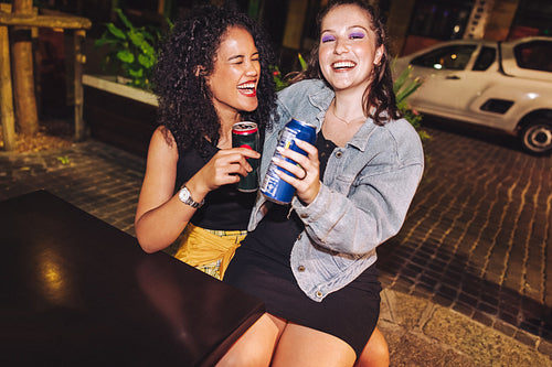 Best friends laughing happily at an outdoors restaurant