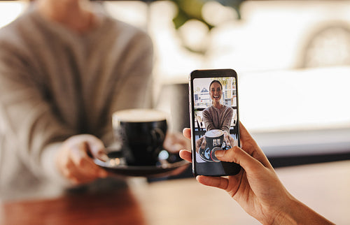 Woman taking pictures of her friend in cafe
