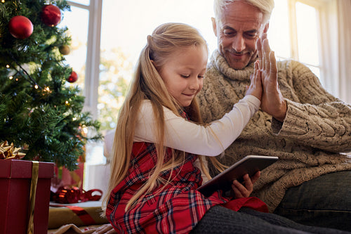 Little girl with grandfather using digital tablet at home