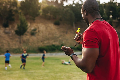 Coach holding a whistle during a training session with school kids
