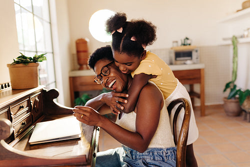Celebrating a mother's love: Little girl hugging her mom at home