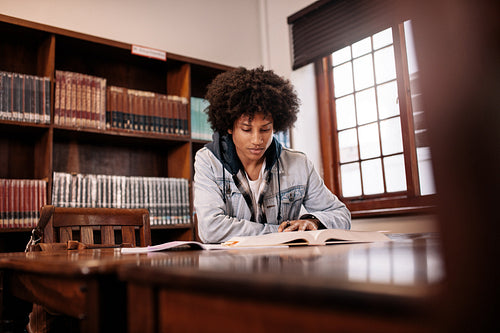 African student reading book in library