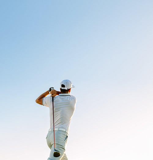 Man swinging golf club against clear sky