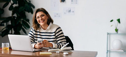 Professional woman working at office desk with laptop and phone communication