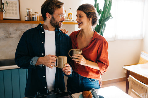 Couple laughing and chatting over coffee in cozy kitchen