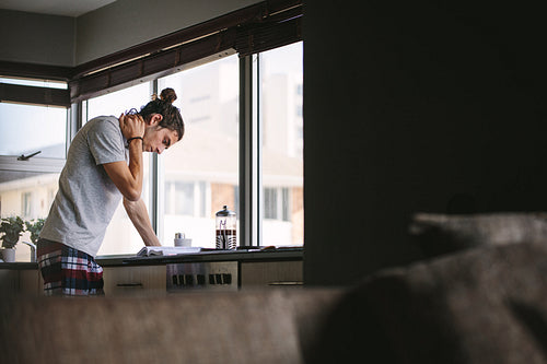 Man reading a book standing in kitchen