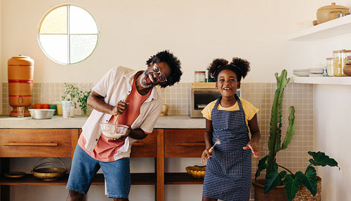 Family fun in the kitchen: Dad and daughter dancing and baking together