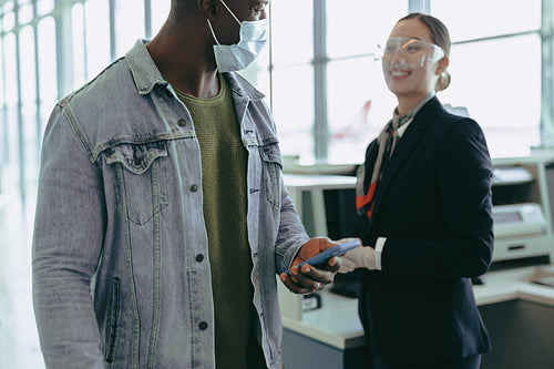 Man in face mask passing by airport check-in counter