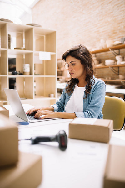 Online store owner using a laptop in a warehouse