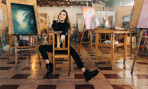 Happy female painter smiling at the camera in her workshop