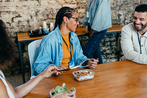Happy coworkers enjoying a casual lunch break together at the office canteen