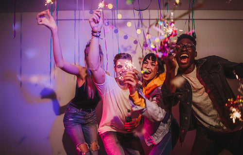 Friends celebrating with sparklers and confetti at a house party