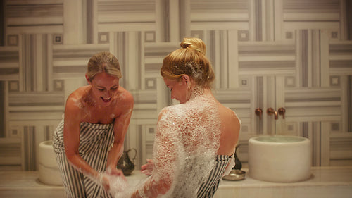 Friends relaxing and enjoying a joyful and foamy traditional hammam spa treatment