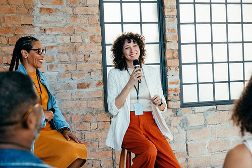 Female speaker leading a workshop and briefing employees with a microphone in modern office