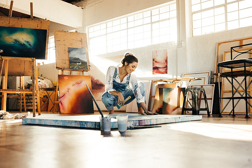Cheerful artist working on a new painting in her studio