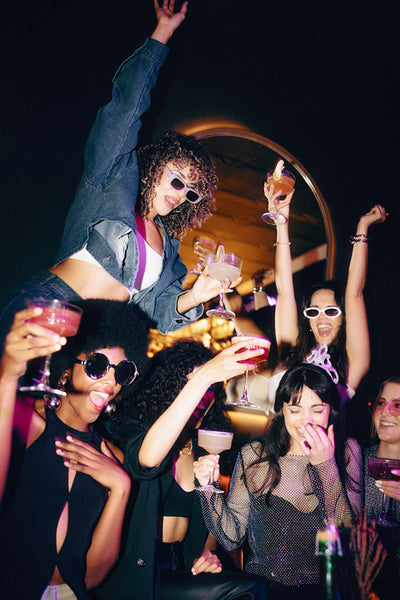 Group of girlfriends celebrating at a lively party with drinks and laughter