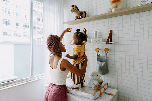Mother lifts toddler for a joyful moment in bright bathroom