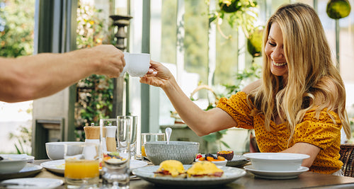 Carefree couple toasting with tea cups at a breakfast table